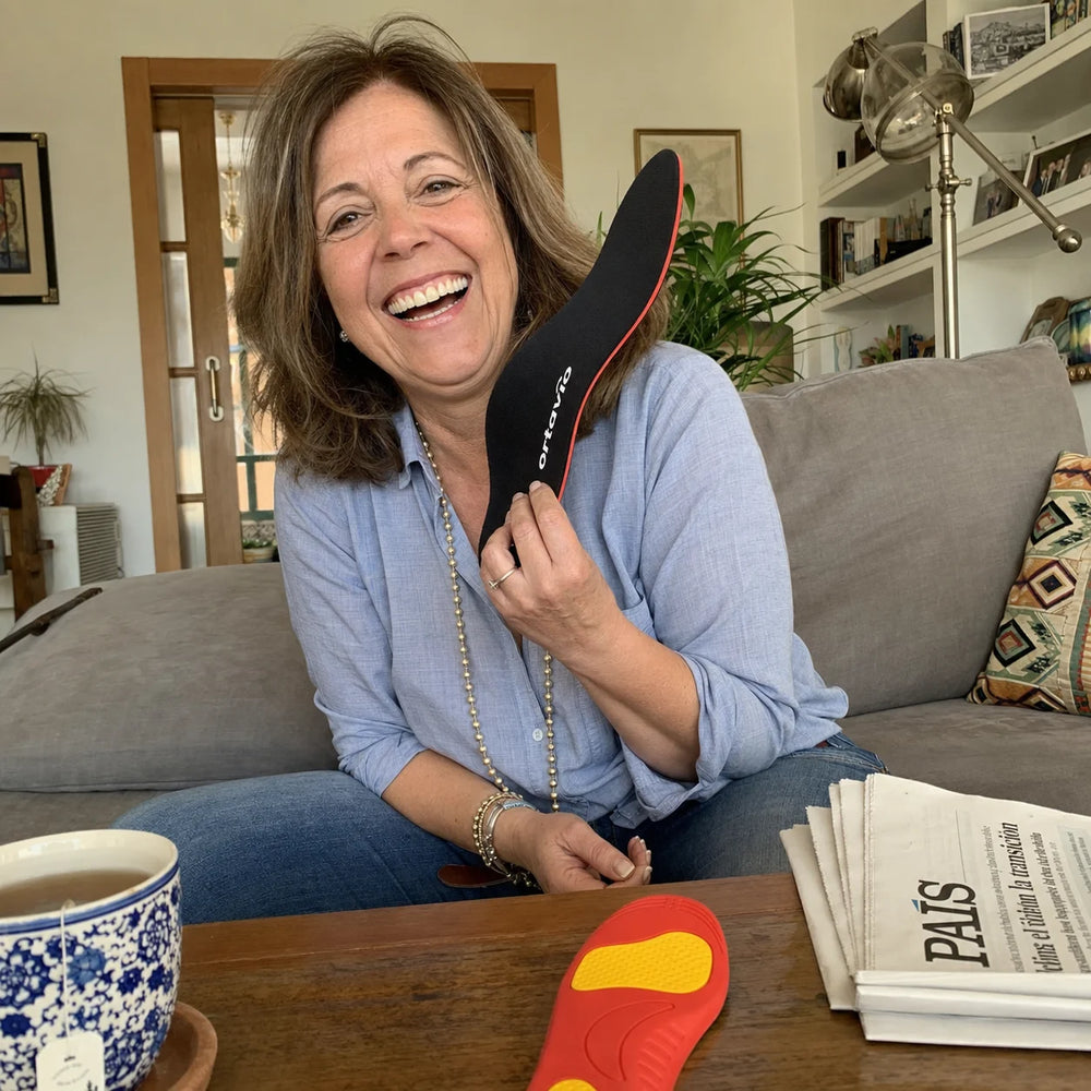 Laura laughing in her living room while showing Ortavio ArcCore insoles